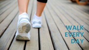 A focused shot emphasizing the action of walking in comfortable athletic shoes on a textured wooden path. The clear call to action, "WALK EVERY DAY", directly links to the numerous walking benefits, promoting consistency as a foundational component of a healthy lifestyle and wellness journey.