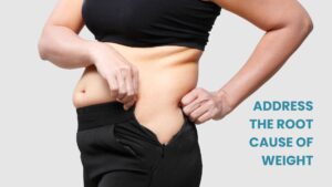 Close-up of a woman pulling on her waistband to show excess abdominal skin and fat, symbolizing weight struggles and the need for weight management.